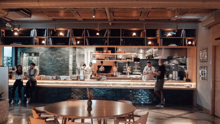 OUR STORY Unrecognizable cooks and bartenders standing at counter near anonymous male client making order in modern cafe